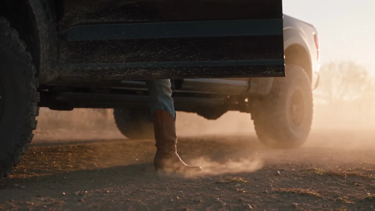 Shot 3, a ground-level camera at 0.22 m. The stand-in only marks where her feet are; the open door and the dust puff are written in the prompt.